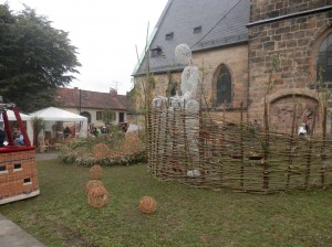 Woven large puppet behind willow fence at Lichtenfels Festival